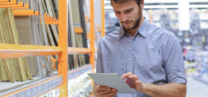 Homem branco, de camisa social, está em uma loja de consturção e usa o Venda Móvel by US4